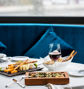 A table set with sharing plates and a glass of red wine